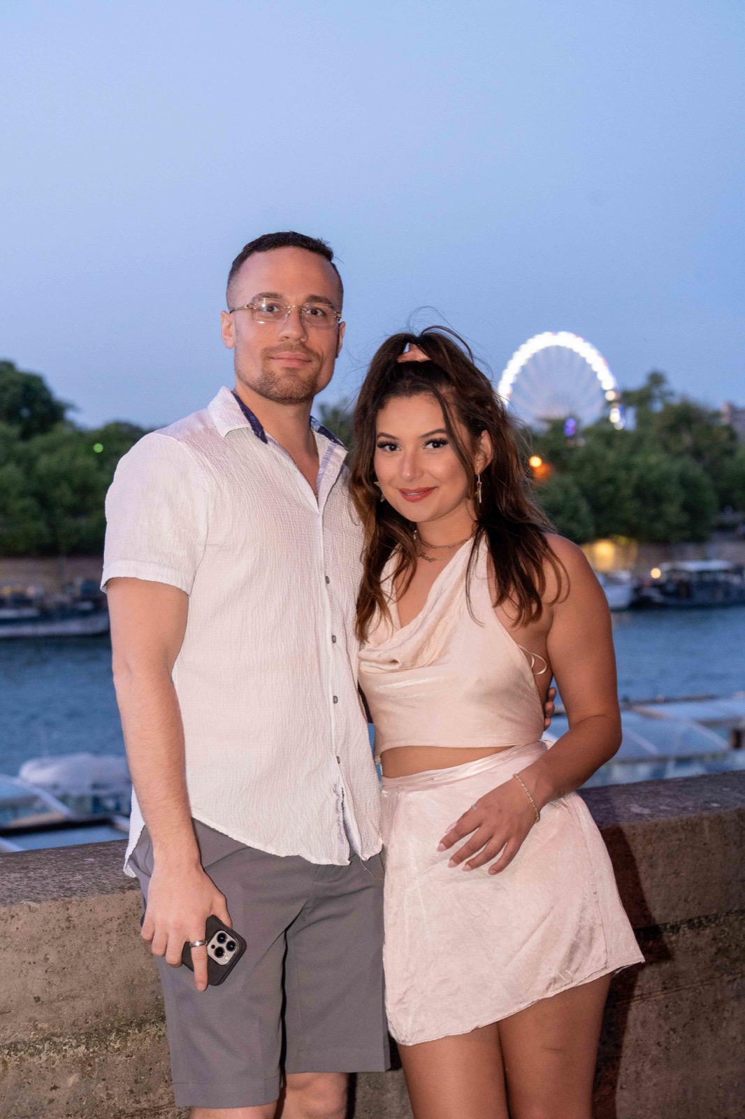 Shooting couple au bord de la Seine le soir à Paris, grande roue en arrière-plan