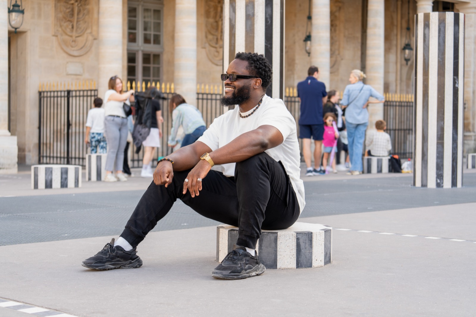 Séance lifestyle à Paris pour homme, portrait souriant sous les arcades du Palais-Royal, lumière naturelle