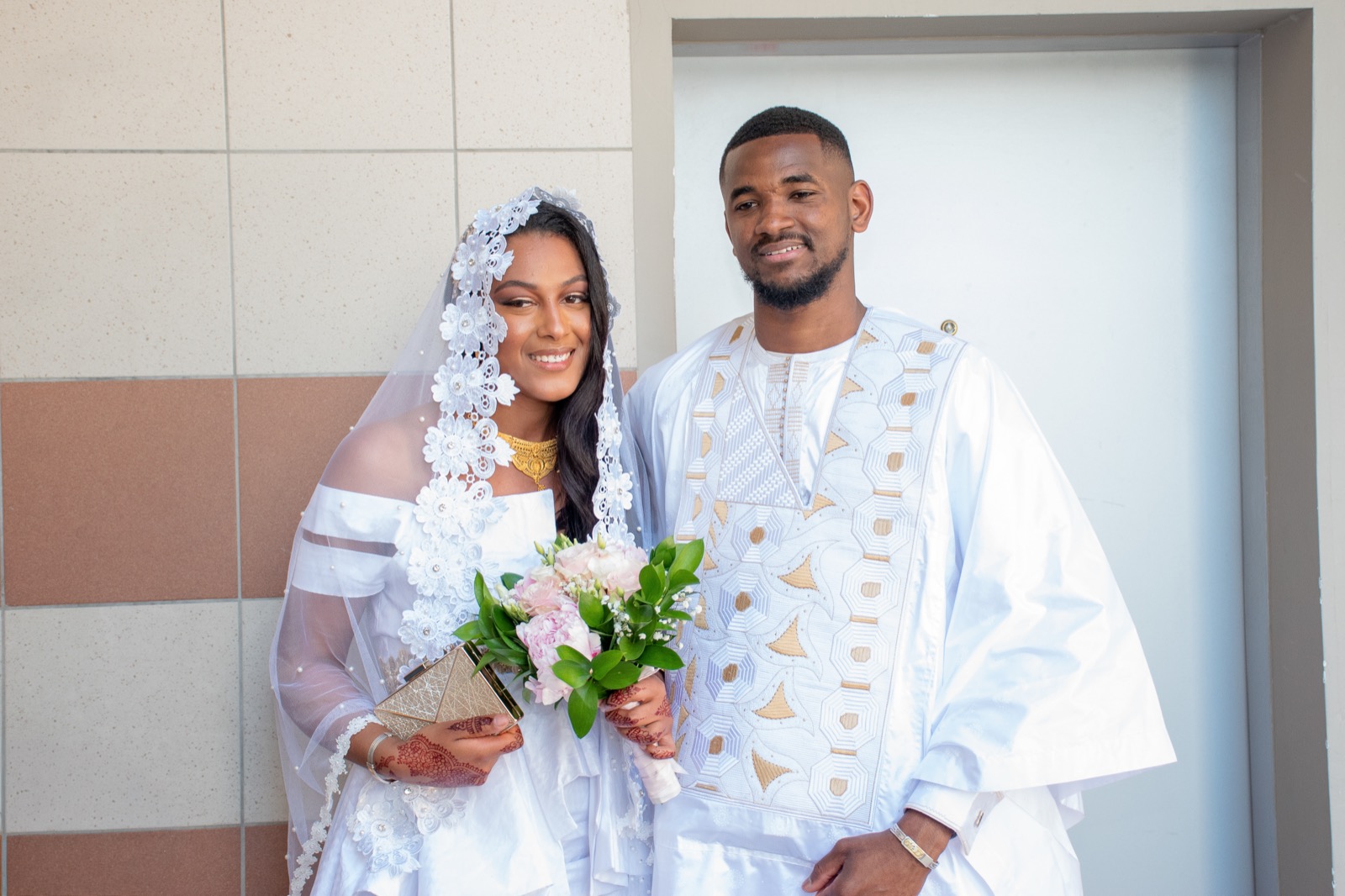 Les mariés en tenue blanche traditionnelle, bouquet à la main