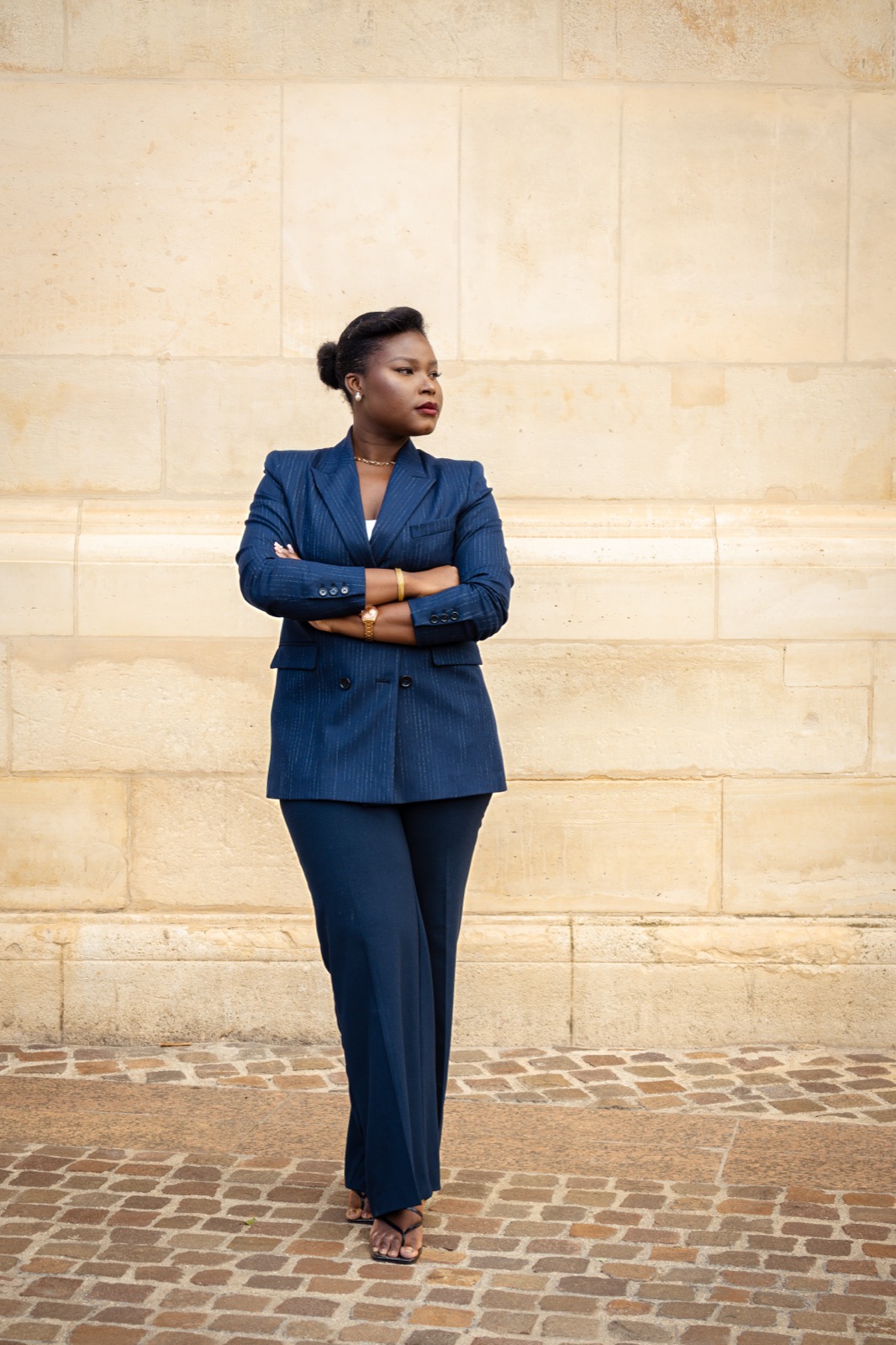 Personal branding Paris, femme en costume marine adossée à un mur de pierre, portrait éditorial